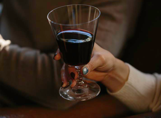 Hand toasting with glass of red wine